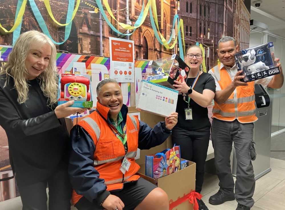 Four Yarra trams employees hold up toys