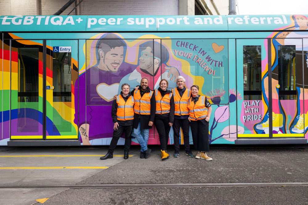 Five Switchboard representatives in high visibility vests pose in front of the Switchboard C class tram with the words